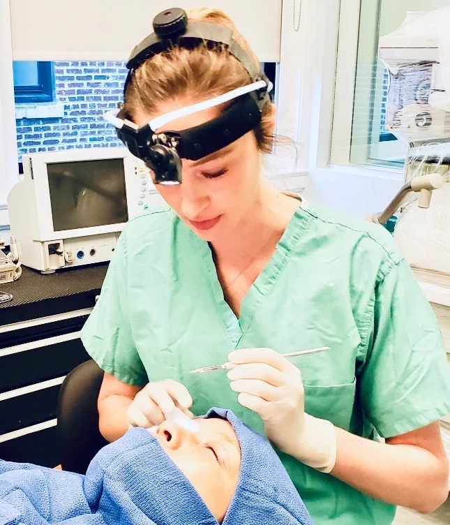 Dr. Noud and a colleague in full sterile surgical blue scrubs giving a "thumbs up" during a procedure in a high-tech operating suite.