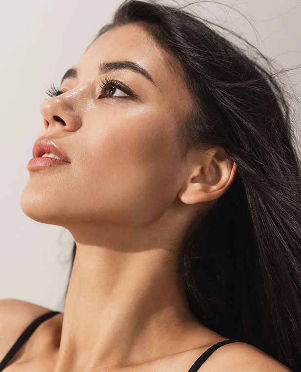 A low-angle, profile portrait of a woman with a defined jawline and sculpted cheeks, highlighting the aesthetic results typically sought through buccal fat removal.